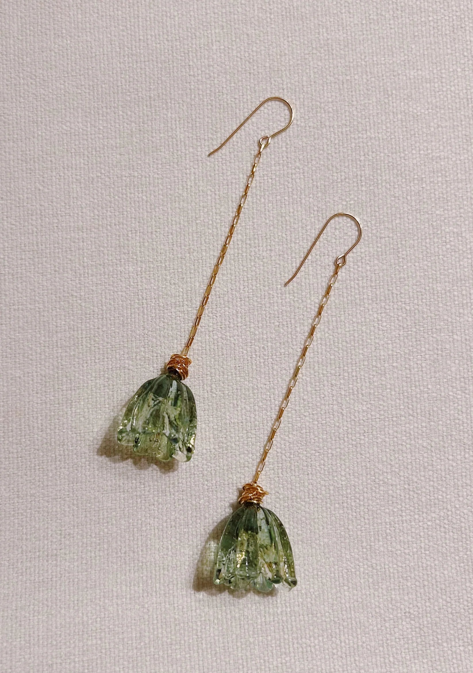 Glass Tulip Earrings in jade feature long gold hooks and delicate, translucent handmade tulip details, expertly crafted by skilled glass artists and shown on a light textured background.