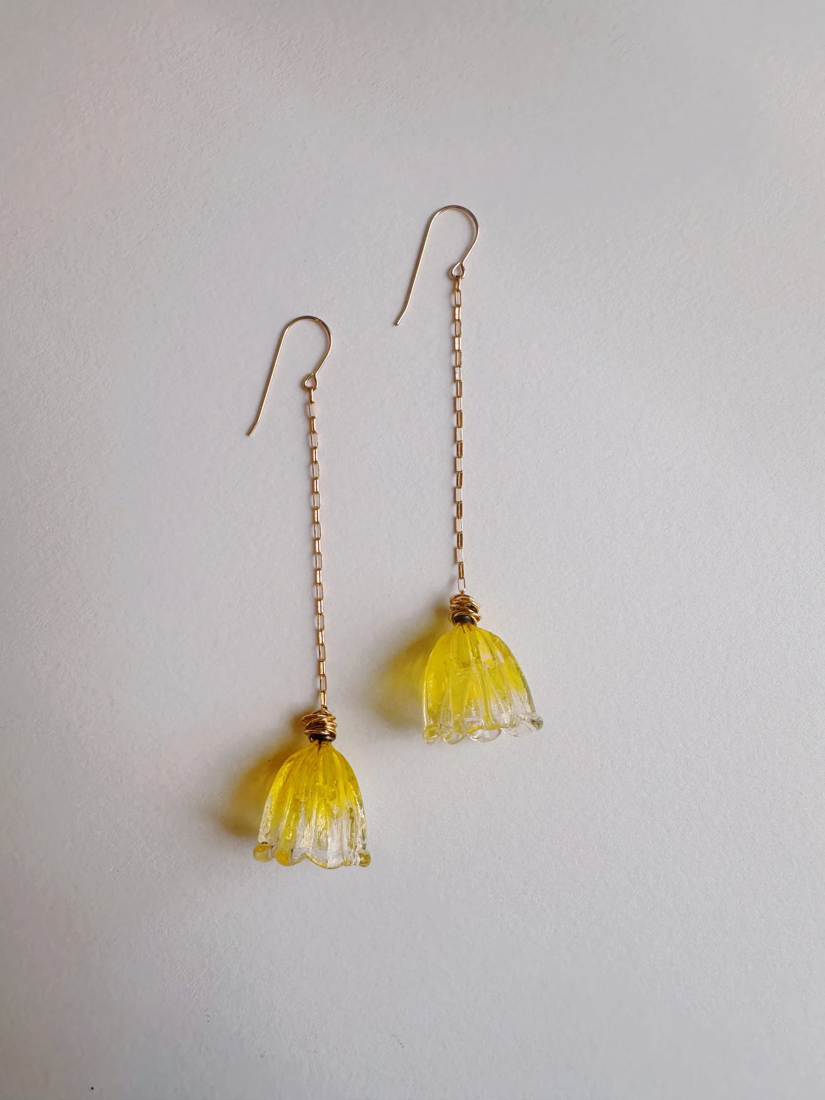 Glass Tulip Earrings in lemon color feature long, thin 14k gold-filled chains with handmade yellow lampwork tulips by a glass artist at the ends, shown on a plain white background.