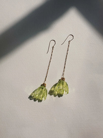 Glass Tulip Earrings in light lime feature delicate 14k gold-filled chains with handmade translucent green lampwork tulips, shown on a white textured surface with gentle sunlight and soft shadows.