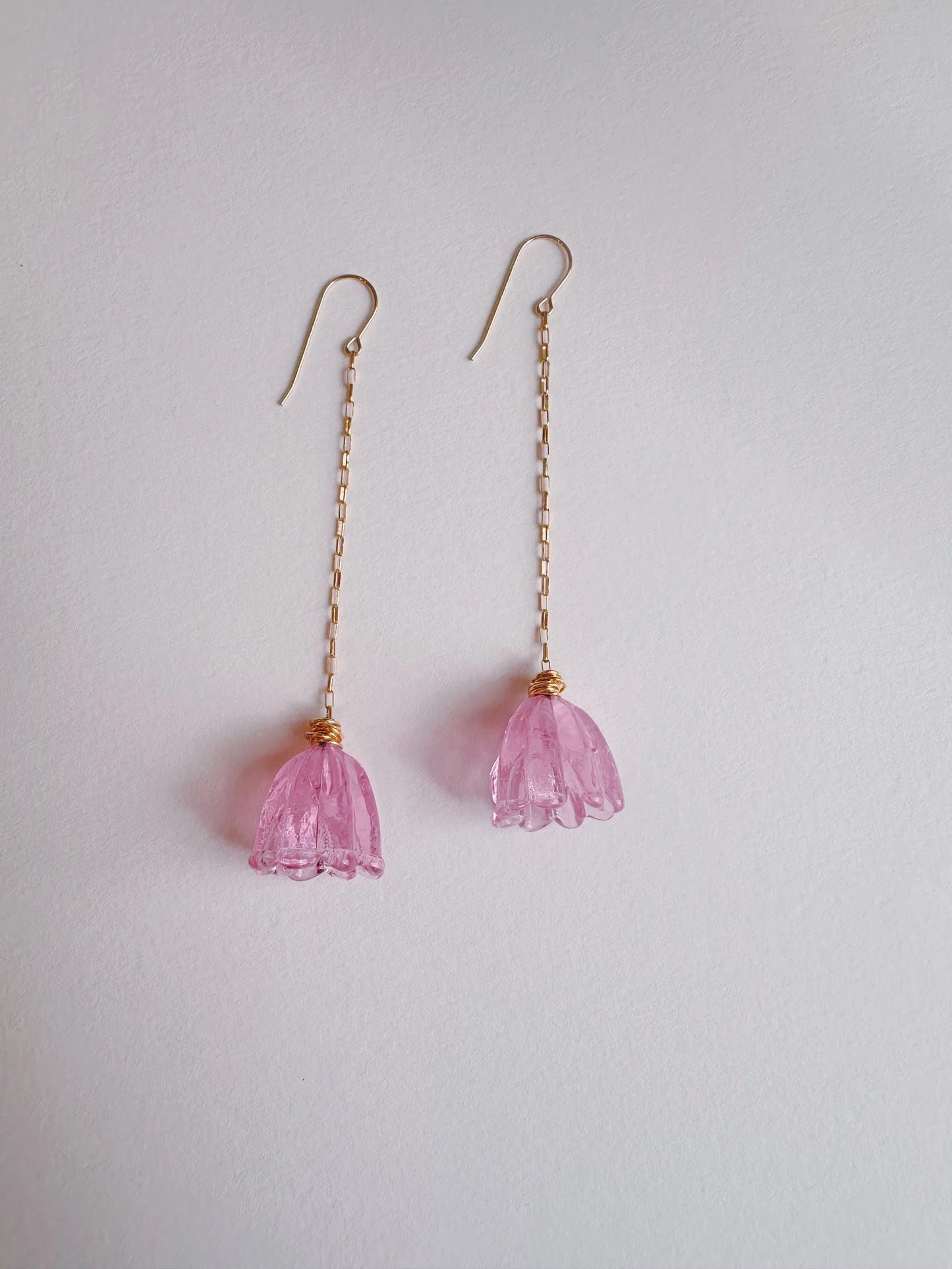 The Glass Tulip Earrings feature ballerina pink, translucent handmade lampwork tulip pendants on long 14k gold-filled chains, artisan-crafted and displayed against a plain white background.